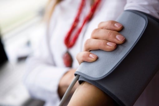 Patient holds arm while getting blood pressure taken by a sphygmomanometer.